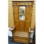 A neat vintage oak hall stand with seat, side umbrella holders and centre swing mirror, also with