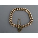 A NINE CARAT GOLD CURB BRACELET with padlock clasp and safety chain, 13.2 grms