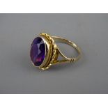 A NINE CARAT GOLD DRESS RING with oval amethyst in a twist setting, 1.9 x 1.3 cms, 4.7 grms, size '