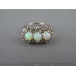 AN EIGHTEEN CARAT WHITE GOLD OPAL & DIAMOND CLUSTER DRESS RING having three round cut opals in an