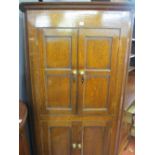 AN ANTIQUE OAK ONE PIECE STANDING CORNER CUPBOARD, twin upper and lower panel fronted doors of peg-