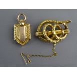 A VICTORIAN PINCHBECK OPEN WORK BROOCH and a shield shaped pendant locket