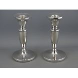 A PAIR OF SILVER CIRCULAR BASED PLAIN SHORT STEMMED CANDLEHOLDERS (loaded), 14 cms high,