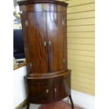 AN ANTIQUE REPRODUCTION TWO PIECE CORNER CUPBOARD, the upper section having two bow fronted doors