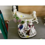 Continental cherub decorated flower basket in the form of a cart and a porcelain group of three