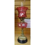 An antique oil lamp with black ceramic and brass base, pink glass reservoir and shade Condition