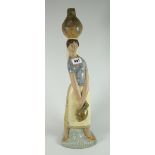 A Lladro pottery model of a water carrying female with vessel on her head, 47cms high Condition