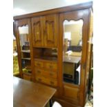An Edwardian mahogany wardrobe, chest of drawers and linen cupboard combination with flanking