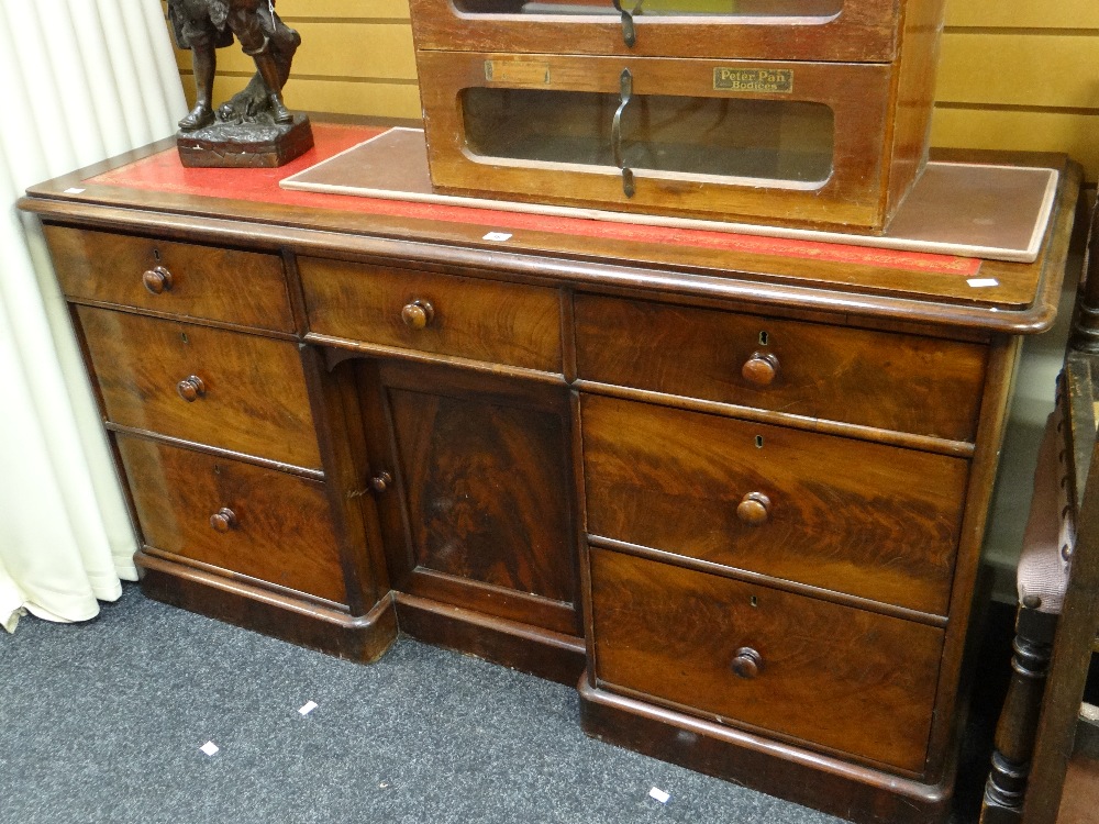 A Victorian mahogany desk of shallow proportions and having centre cupboard flanked by three