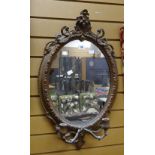 An antique gilt framed oval wall mirror with candle sconce base, 73cms high Condition reports