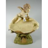 An imposing Royal Dux pottery model of a cherub gazing at a frog inside a clam over a naturalistic