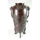 A tall bronze Chinese temple vase of ovoid form on four dragon feet and with beast-mask terminals to