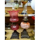 Two antique oil lamps - both with pierced metal square form bases, one with cranberry glass