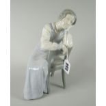 A B&G Copenhagen porcelain figure of a lady in a long night-dress leaning on her hand, 23cms high