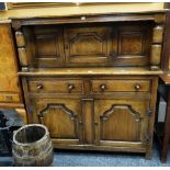 An antique reproduction panelled court cupboard, the base with two cupboards, two drawers and with