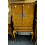 A vintage polished burr wood standing two-door cocktail cabinet with base drawer on cabriole