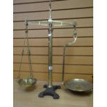 An antique set of brass provision balance scales on a decorative cast iron base inscribed