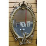 An antique gilt framed oval mirror having a shell and laurel finial and three-branch candle