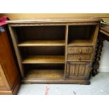 A reproduction oak open bookcase with two drawers and linen fold cupboard, 93cms wide