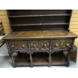 A vintage oak Jacobean-style dresser having an open rack and moulded and carved three-drawer base,