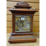 A GERMAN WALNUT ENCASED MANTEL CLOCK having a brass dial with silvered chapter ring bearing Roman