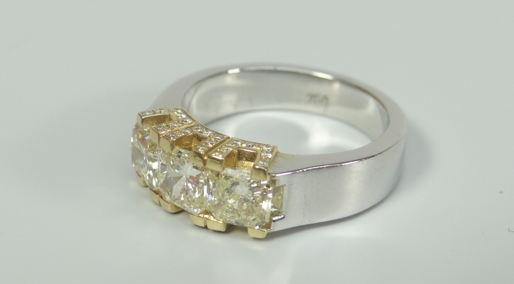 18CT WHITE GOLD THREE STONE YELLOW DIAMOND RING, having further diamond chips to setting. Total