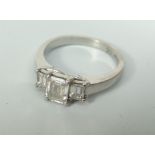 PLATINUM SET LADIES THREE STONE EMERALD CUT DIAMOND RING. The central stone an approximate weight of
