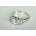 WHITE METAL EMERALD CUT FIVE STONE DIAMOND RING, set with five graduated diamonds. Total diamond
