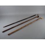 THREE VINTAGE DOG HEAD WALKING CANES, to include a carved wood example, 88 cms long, a carved bone/