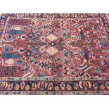An Eastern style woollen carpet with central tree and floral design on a red ground with triple