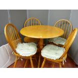 A modern lightwood circular top dining table with four stick back chairs and a portable radiator E/