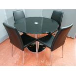 An ultra modern chrome and black glass topped circular dining table and four chairs, 110 cms