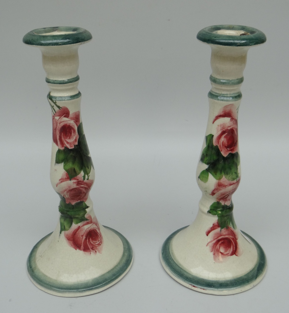 A PAIR OF LLANELLY CANDLESTICK HOLDERS with circular bases and decorated with tea-roses,