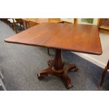 AN ANTIQUE MAHOGANY FOLDOVER TEA-TABLE on shaped scrolling supports and baluster faceted column,