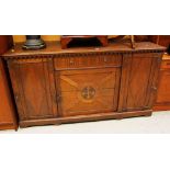 AN ARTS AND CRAFTS STYLE SIDEBOARD with centre heraldic panel, side cupboards and drawer