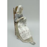 A LLADRO PORCELAIN SCULPTURE OF A SEATED LADY needle-working and wearing a decorative apron, 30cms