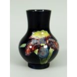A WALTER MOORCROFT SQUAT BALUSTER VASE with Slipper Orchid design to a deep blue ground, 11cms high,