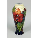 A MOORCROFT POTTERY BALUSTER VASE in the 'Simeon' pattern of flowers and leaves (boxed), 20cms high