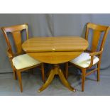 A CIRCULAR DROP LEAF LIGHTWOOD DINING TABLE with two matching upholstered arm chairs