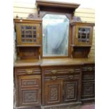 AN EDWARDIAN OAK BREAK FRONT MIRRORED BACK SIDEBOARD having a carved detail, four drawers, four