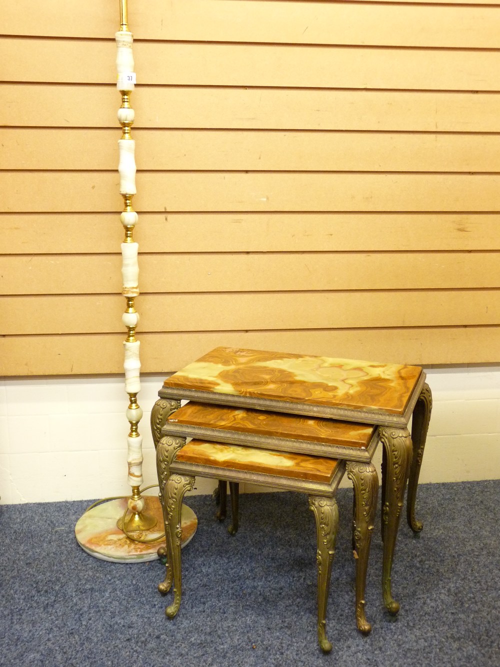 A PSEUDO ONYX AND BRASS STANDARD LAMP with shade on a turned column and circular base and a nest