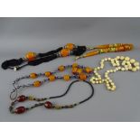 THREE AMBER TYPE NECKLACES and a graduated set of early 20th Century ivory beads