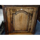 AN ANTIQUE OAK WALL HANGING CORNER CUPBOARD single door with cross banded panel detail and quarter