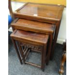 A NEST OF THREE ORIENTAL HARDWOOD COFFEE TABLES with open work carved frieze, largest 46cms wide