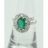 PLATINUM ILLUSION SET EMERALD AND DIAMOND CLUSTER RING, the central oval emerald (8 x 6mm)