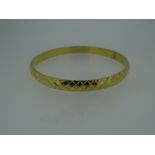 YELLOW METAL LADIES BANGLE OF CRISS-CROSS DESIGN (tested as high carat approximately 22ct gold),