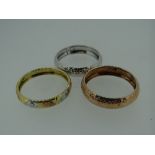 THREE GOLD BANDS, one rose gold, one yellow, white and rose, and one white gold, all stamped '9k',
