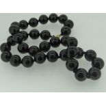STRING OF BELIEVED HEMATITE BEADS with 9ct gold clasp