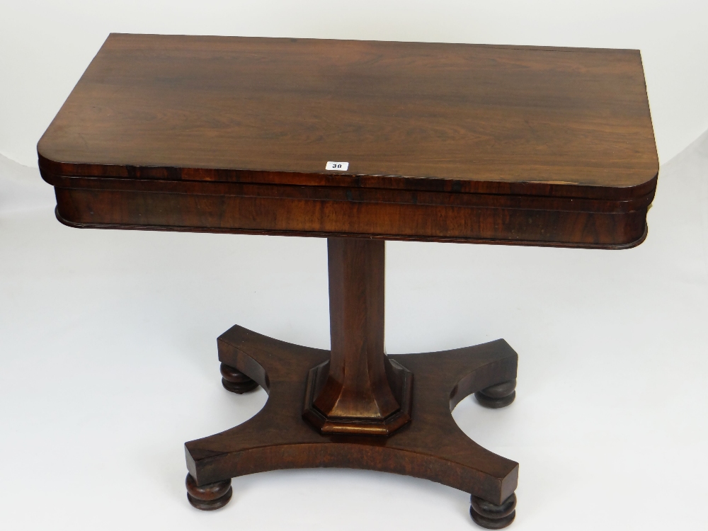 ANTIQUE ROSEWOOD FOLD-OVER CARD TABLE, faceted support on a shaped base with four bun feet, the