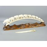 AN INDIAN CARVED TUSK ELEPHANT TRAIN, 49cms length on a polished natural wood stand and an